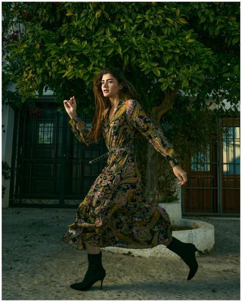 Woman in stylish dress runs on an urban street, sh