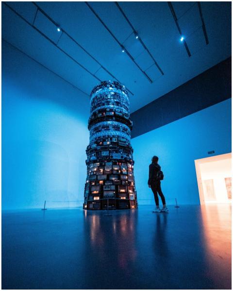 A woman observes a towering modern art installatio