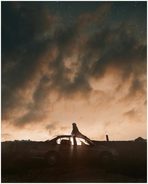 A person stands on a car roof gazing at stars agai