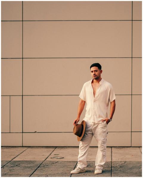 Portrait of a stylish man holding a hat against a