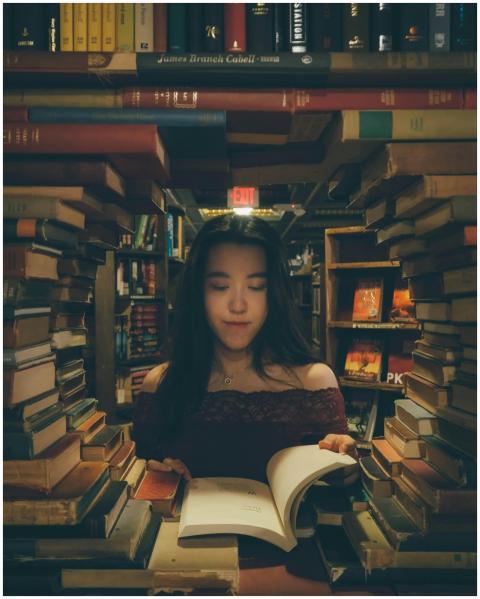 A woman enjoys reading in a cozy bookstore surroun