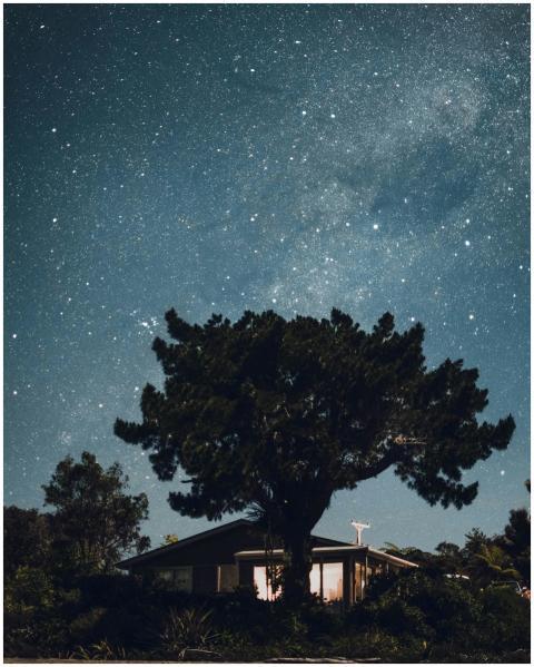 A tranquil night sky filled with stars over a rura