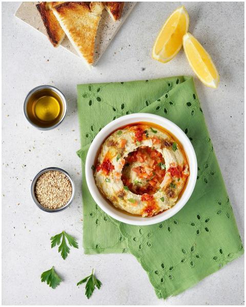 Appetizing hummus dish with garnishes, toast, and