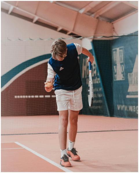 A young tennis player prepares to serve the ball o