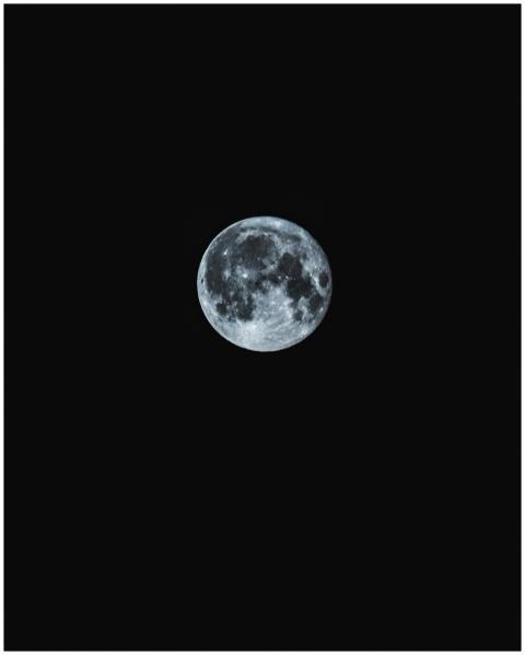 A stunning full moon shining brightly against a da