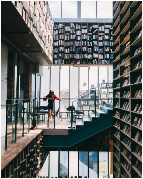 A modern library with towering bookshelves and gla