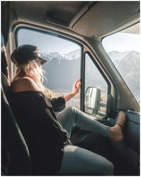 Young woman sitting in van, enjoying mountain view