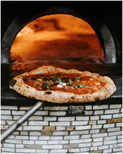 Freshly baked Neapolitan pizza emerging from a woo