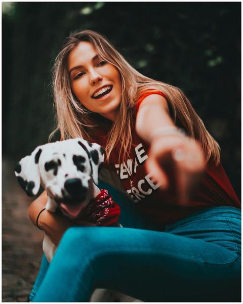 Happy woman with a Dalmatian dog pointing forward