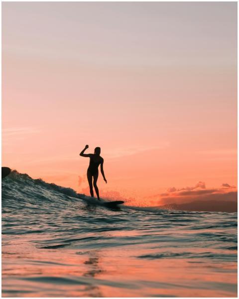 Silhouette of a surfer enjoying the waves at sunse