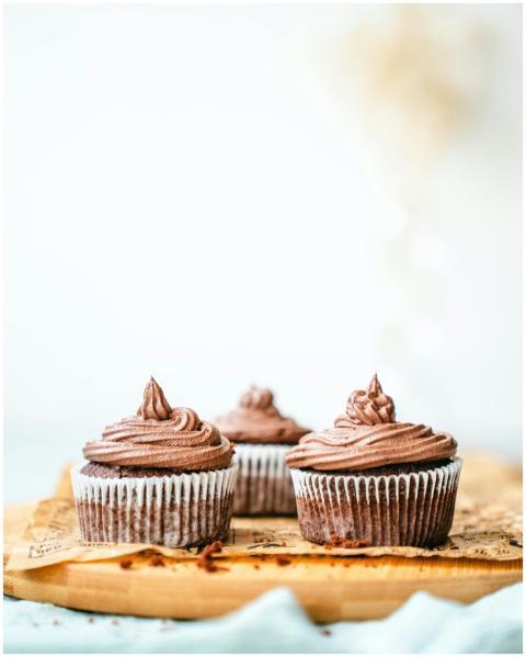 Three chocolate cupcakes with creamy frosting on a