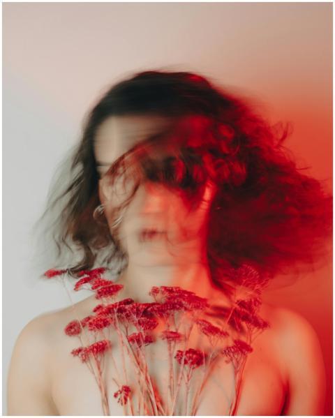 Creative blurred portrait of a woman holding red f