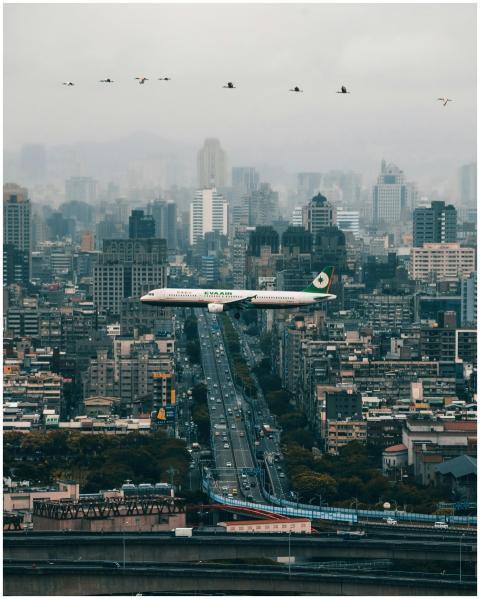 A passenger airplane flying over Taipei's skyline