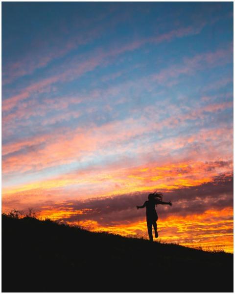 An individual dances joyfully against a vibrant, c