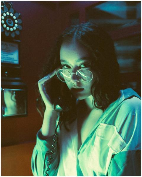 A young woman with glasses uses a retro landline p
