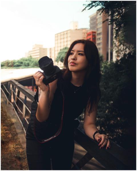 Asian woman holding a camera in an urban outdoor s