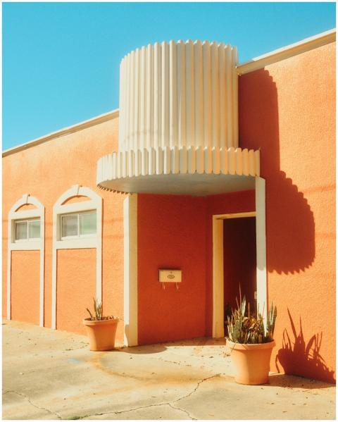 Sunny outdoor view of an orange house with potted