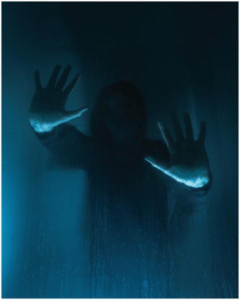 Mysterious silhouette with hands on foggy glass, e