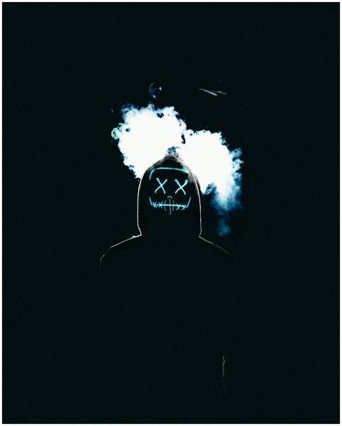 Silhouetted figure with glowing mask and smoke cre