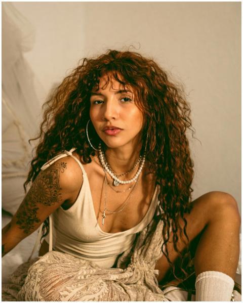 A fashionable woman with curly hair, tattoos, and