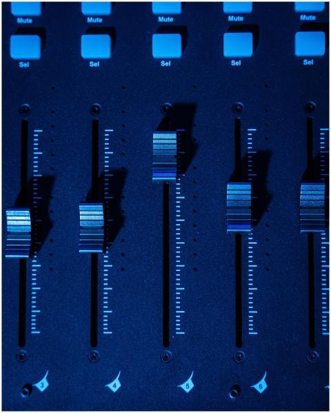 Detailed shot of a mixing console faders with blue