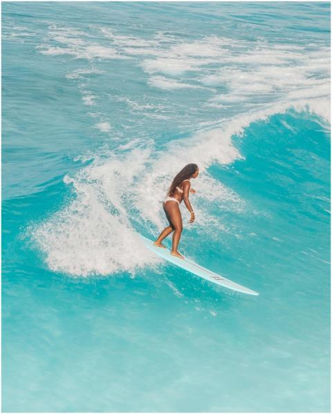 Woman surfing on blue ocean waves, showcasing wate