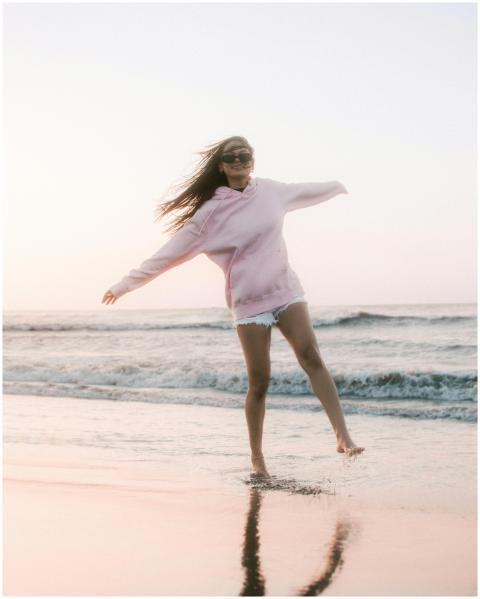 A carefree woman frolics along the beach at sunset