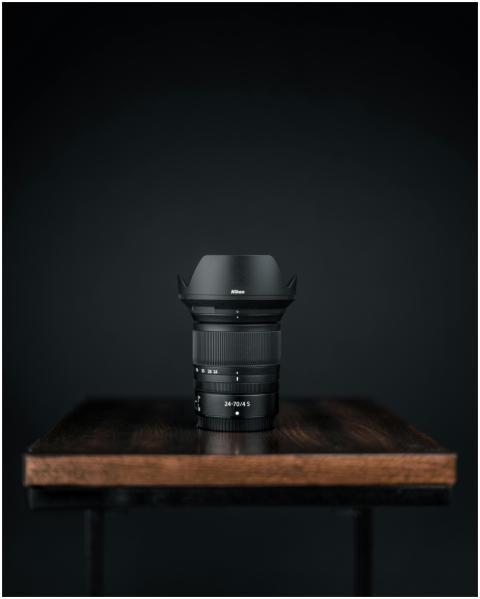 Close-up of a black camera lens on a wooden table