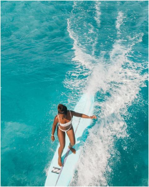 Woman surfing on turquoise ocean waves, capturing