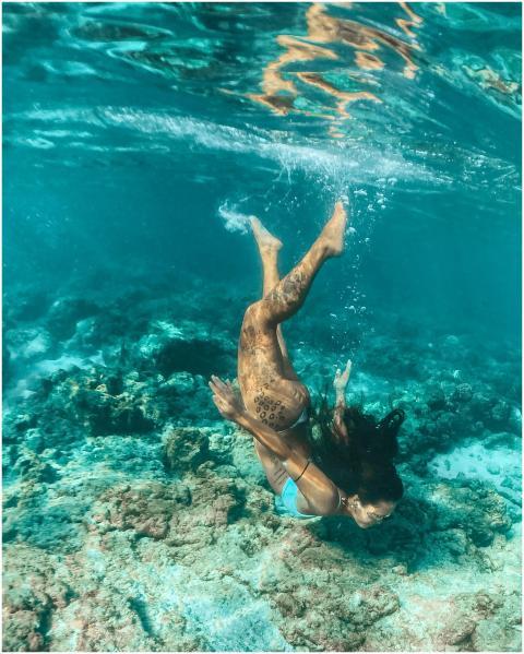 Capture of a woman freediving gracefully over a co