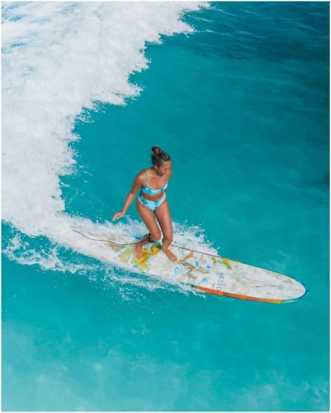 High-angle shot of a woman surfing on clear turquo