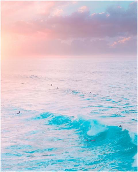 A stunning aerial view capturing surfers in turquo