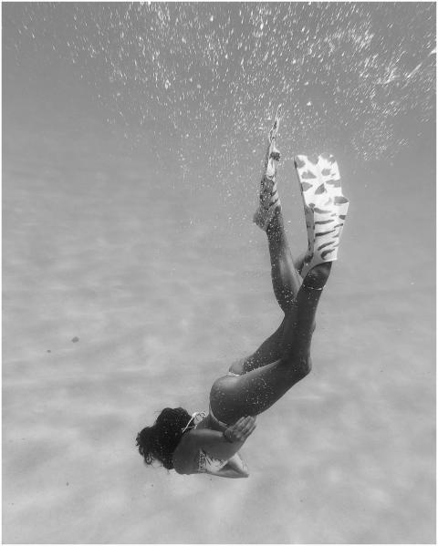 Black and white image of a person diving underwate