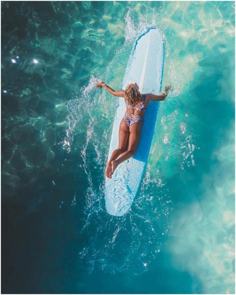 Aerial view of a woman on a surfboard in a bright