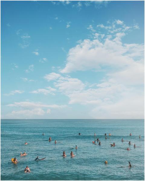 Surfers and swimmers enjoy a sunny day on a pristi