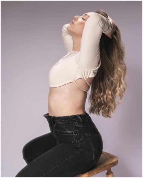 Elegant woman with long hair poses on a stool, exu