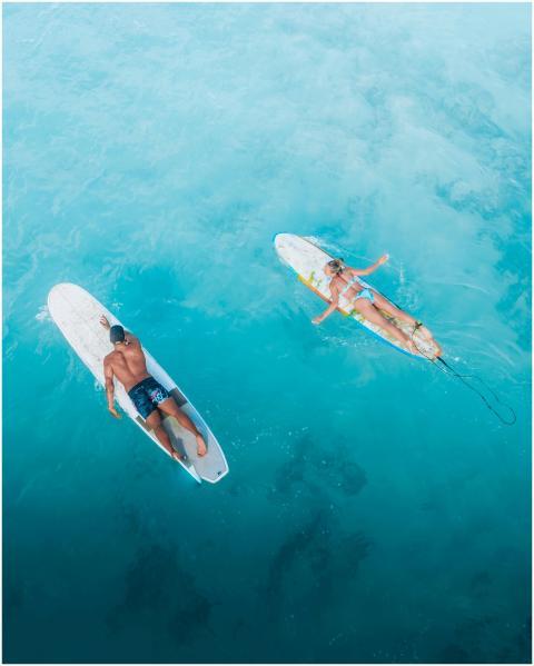 Two surfers lying on surfboards in bright blue oce