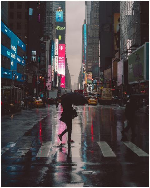 A person with an umbrella crossing Times Square at