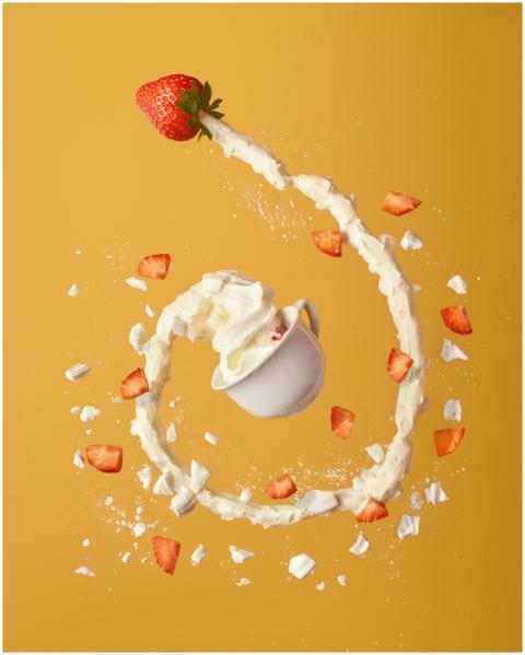 Dynamic splash of whipped cream and strawberries i