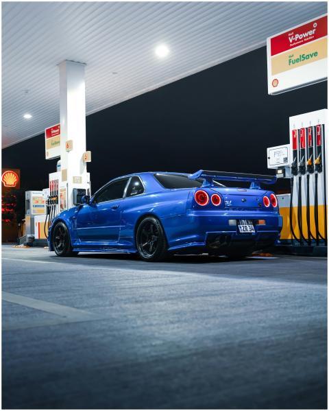 A sleek blue sports car parked at a gas station at