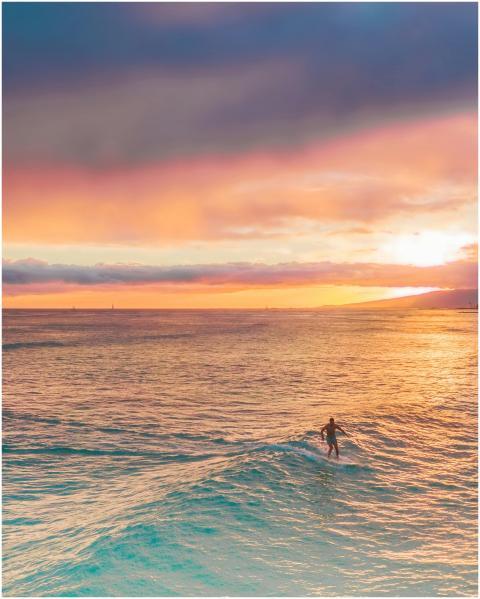 A lone surfer embraces the setting sun with vibran
