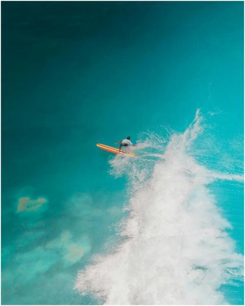 Stunning aerial shot of a surfer riding a vibrant