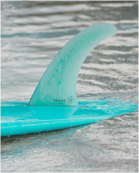 Close-up of a teal surfboard fin partially submerg