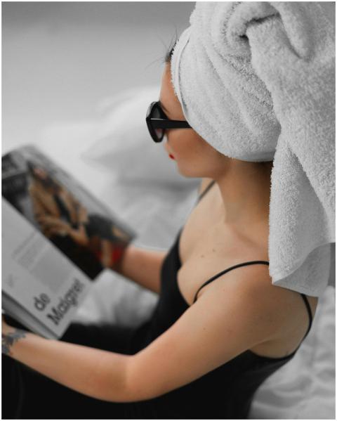 Woman with towel and sunglasses reading a magazine