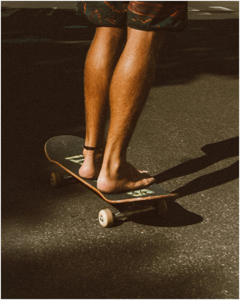 Close-up of a person's legs skateboarding barefoot
