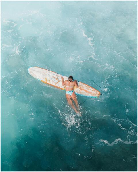 Woman surfing in clear blue ocean waters, showcasi
