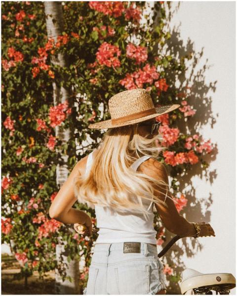 Woman with long blonde hair in a straw hat walking