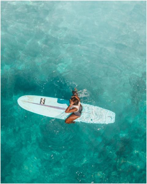 Aerial shot of a woman relaxing on a surfboard in