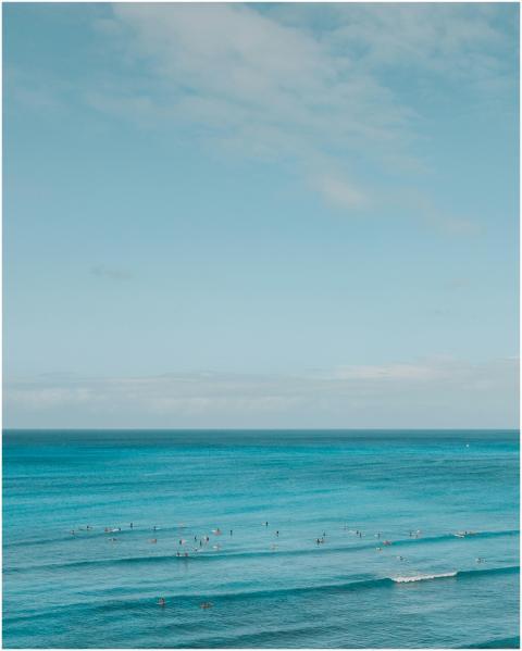 Turquoise ocean waves with surfers capturing seren