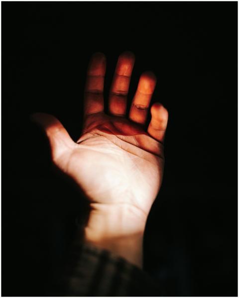 A close-up of an outstretched hand lit dramaticall